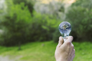 Pessoa segurando uma lâmpada com a imagem do planeta Terra, simbolizando inovação e sustentabilidade dentro de uma estratégia climática corporativa.